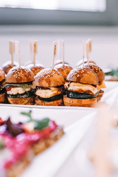 Veganské mini hamburgery na bílém talíři na cateringovém stole